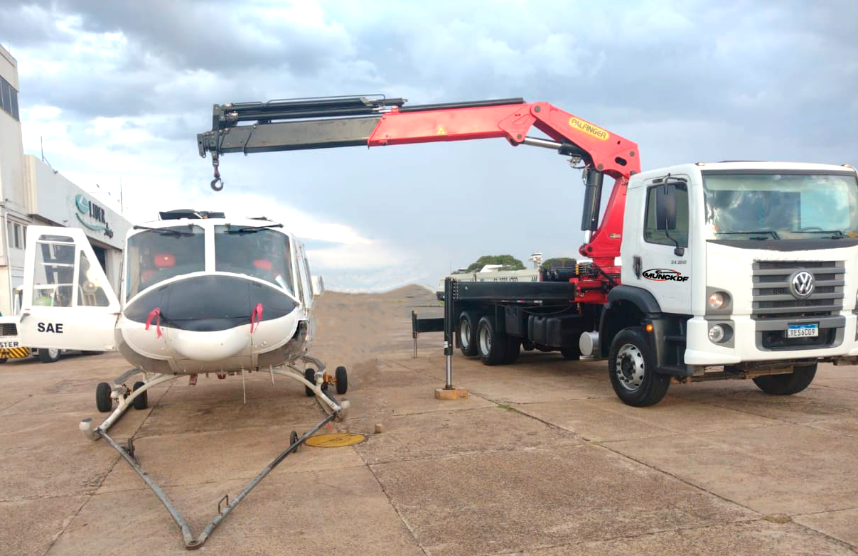 Caminhão Munck ao lado de helicóptero